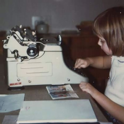 Angela Ward as a child, using a typewriter